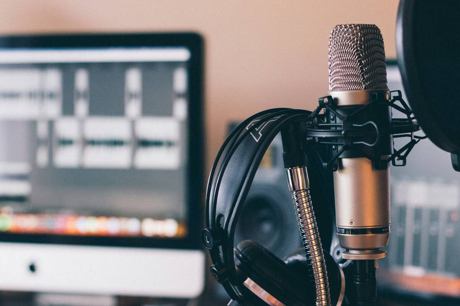 Podcast host recording in a cozy studio with headphones and microphone